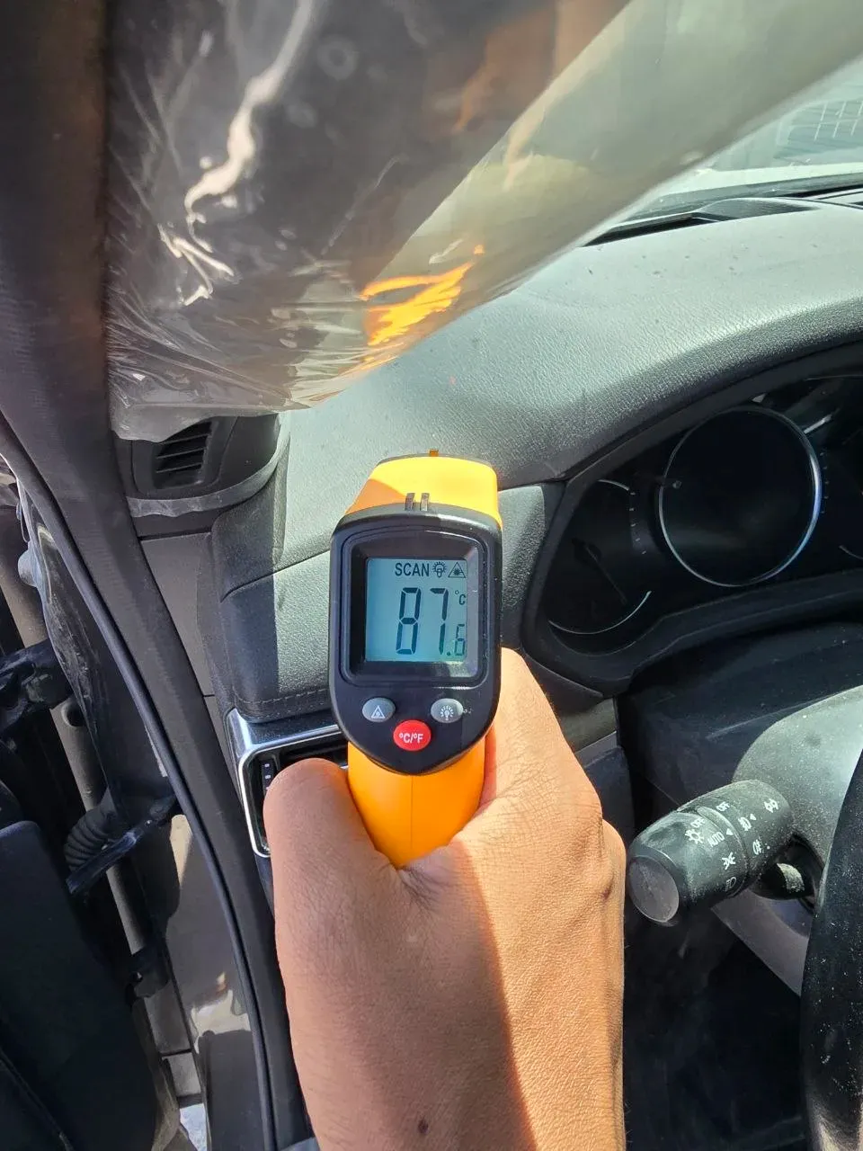 The same infrared thermometer reading 87.6C on a shaded part of the dashboard
